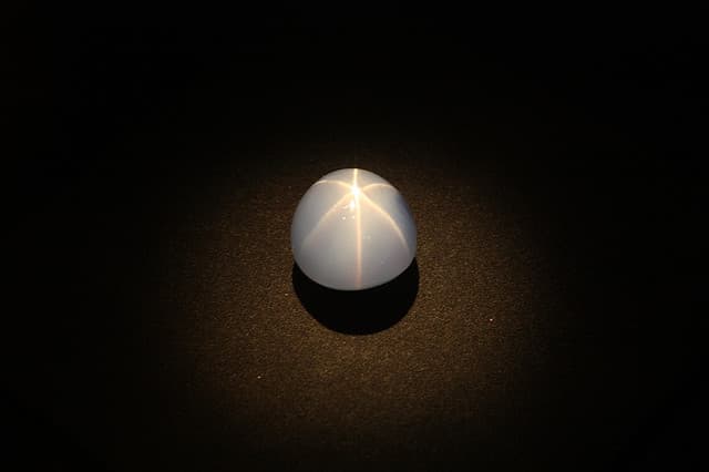 While asterism in other gemstones, like this sapphire, is caused by inclusions, the star effect in opals is caused by the diffraction of light from imperfections in the arrangement of silica (SiO2) in the stones. 