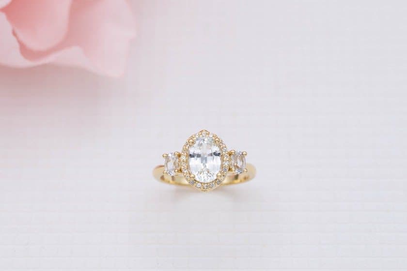 Oval-cut white sapphires in a three-stone halo setting